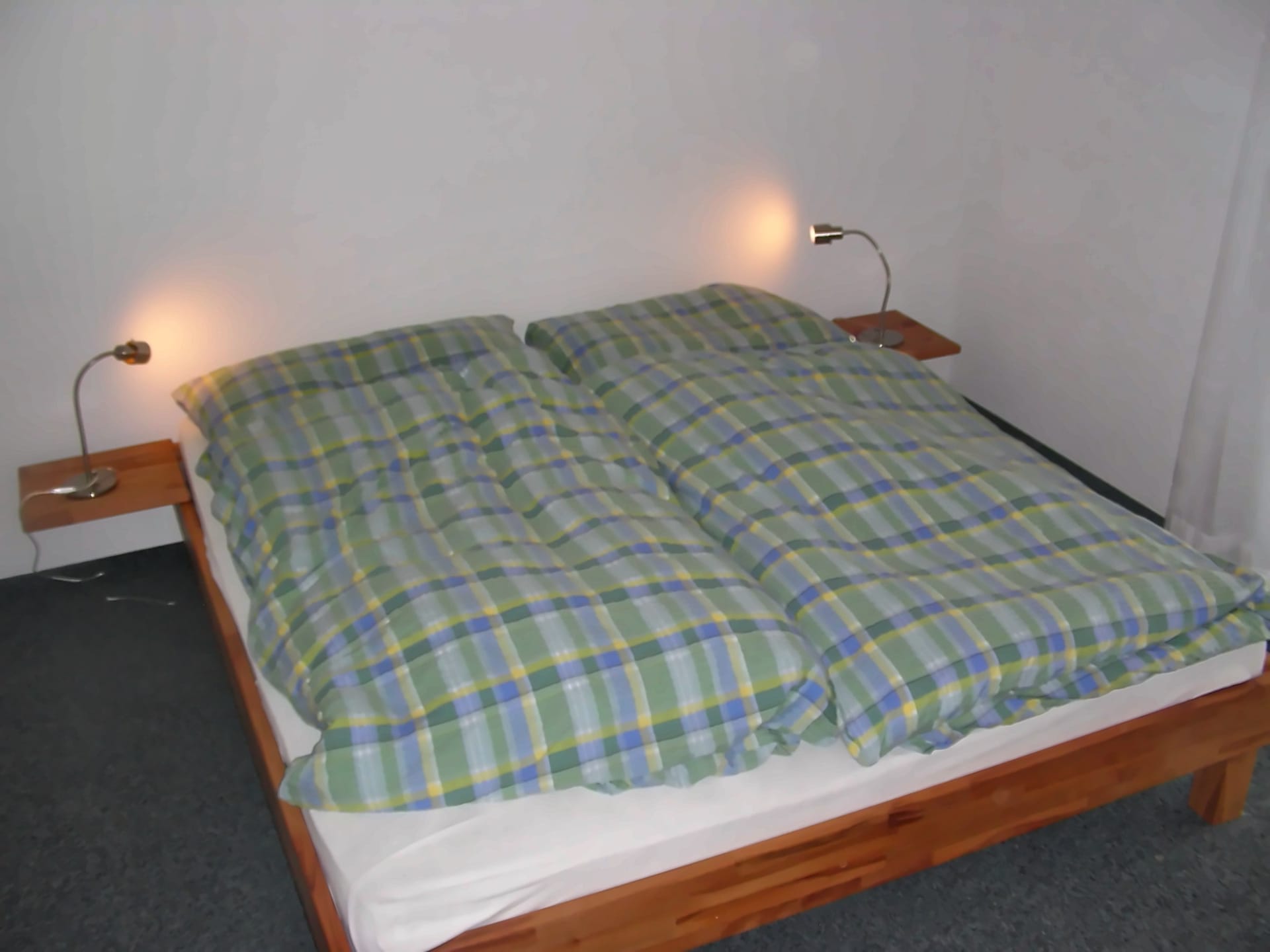 Helles Schlafzimmer mit Doppelbett aus Holz und Nachttischen mit Leselampen