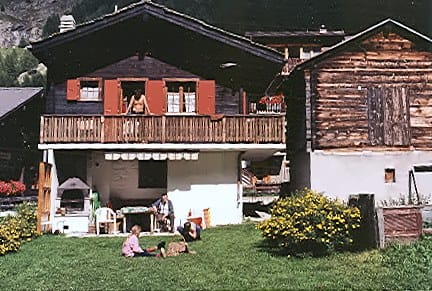 Das alte Adlerhorst 1994: dunkles Walliser Holzhaus mit Balkon, davor Familie im Garten